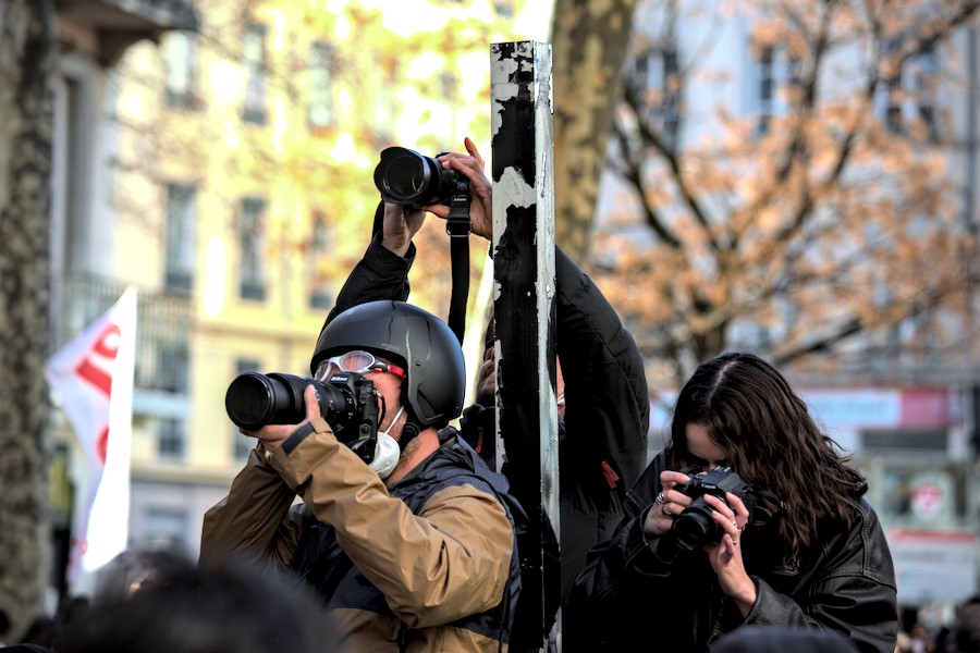 Trois photographes juché·es sur un même pylône, leurs objectifs dans des directions différentes.